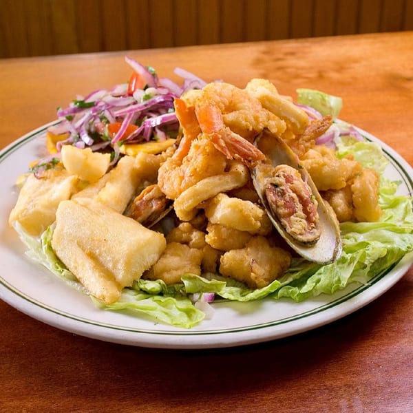 Mambo's Cafe's fried seafood platter with shrimp, mussels, and fish, served with red onion salad and lettuce.